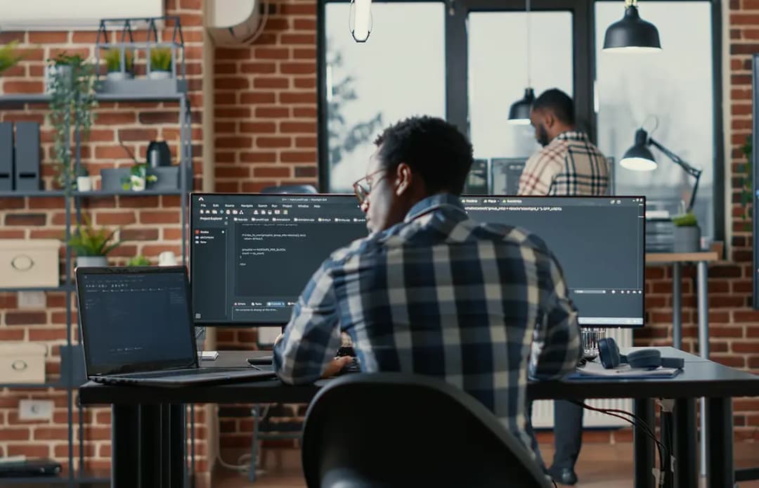 Developer working at workspace with multiple monitors